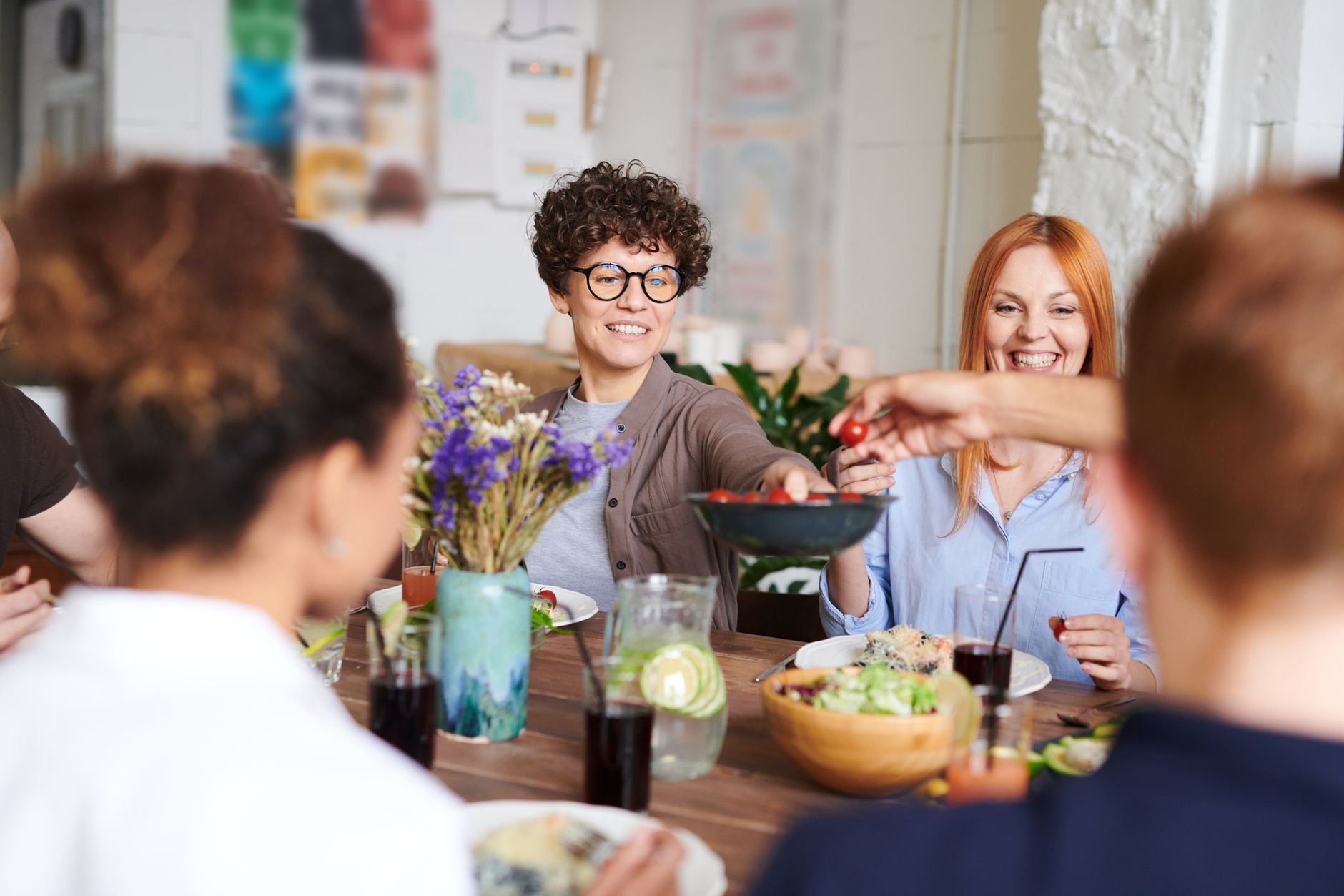 A happy group of women and families enjoying a meal together — warmth, togetherness, real life.